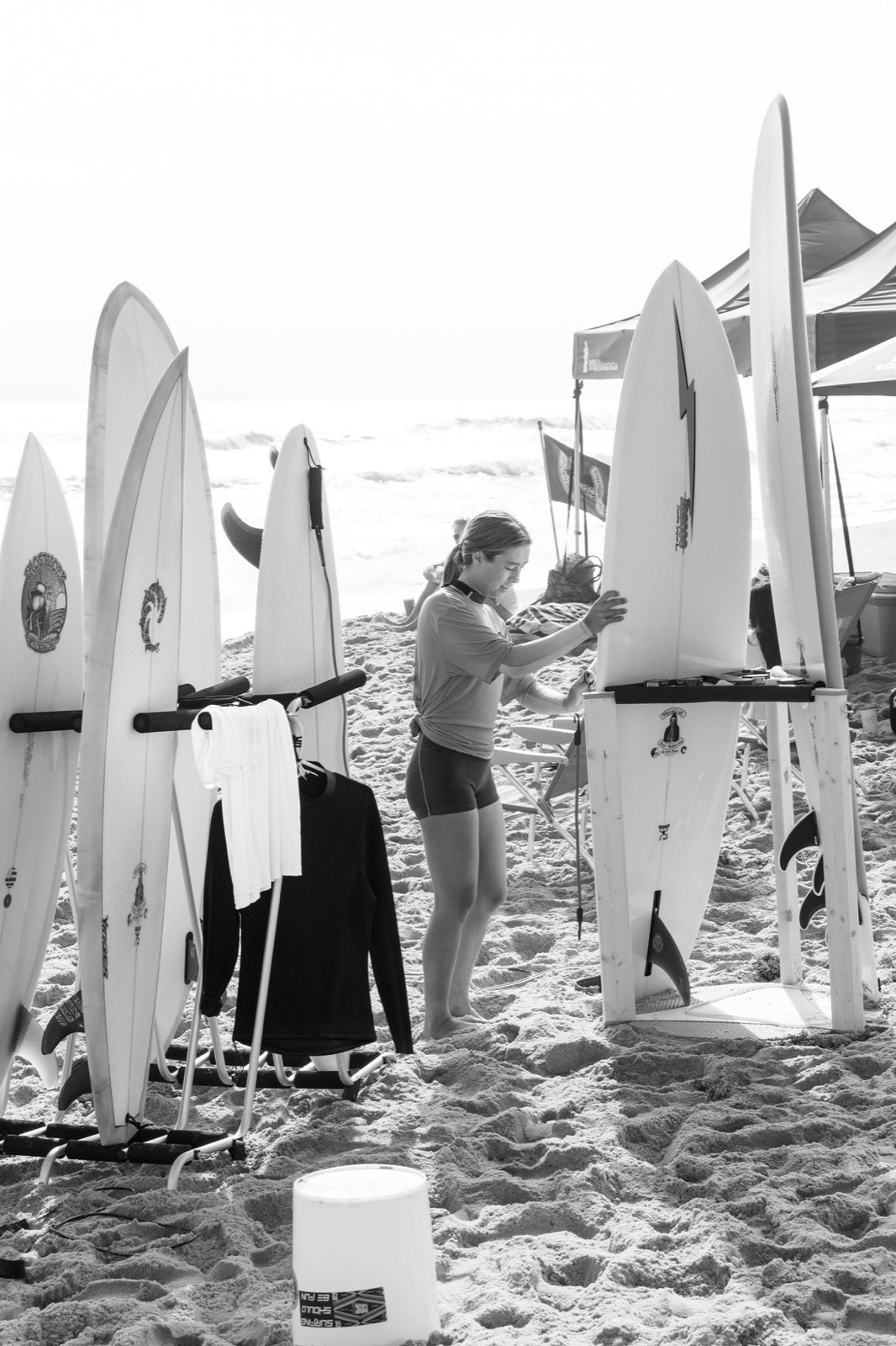 Hand-shaped surfboards racked in the sand, black and white