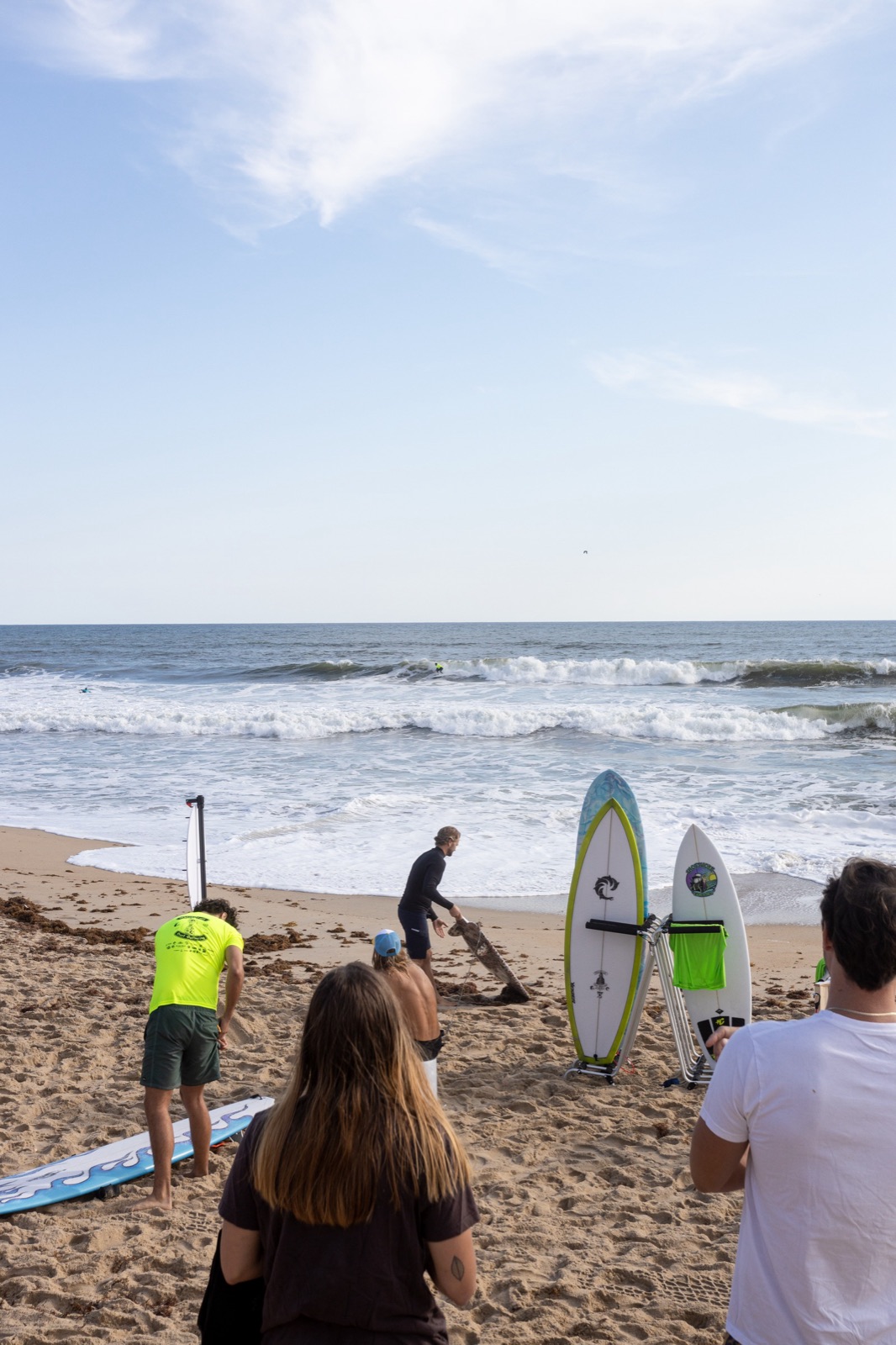 Surfers and spectators gather at the water's edge before a heat