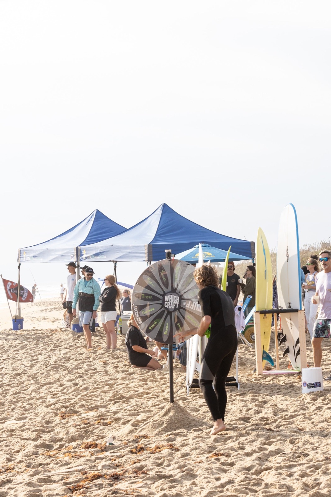 A wetsuited surfer spins the Which Craft board wheel on the beach